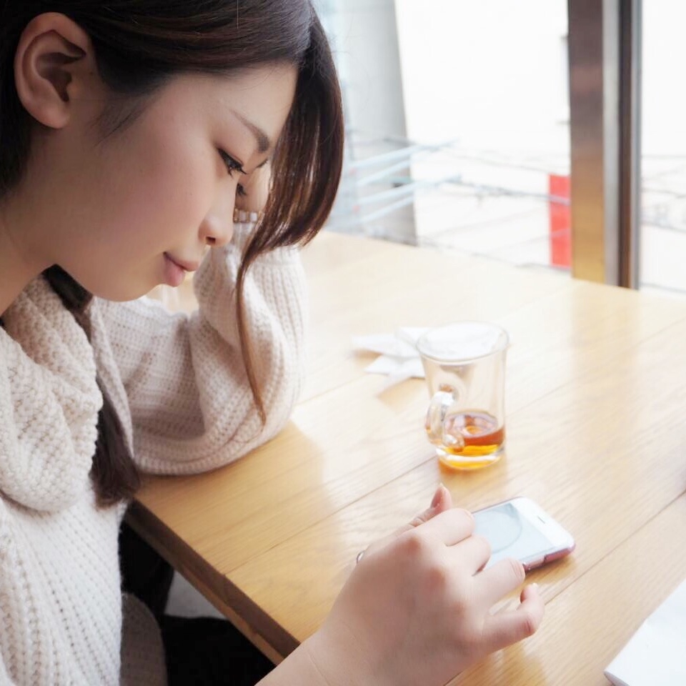 Haruka Shibata sits at a table and uses the phone with her finger